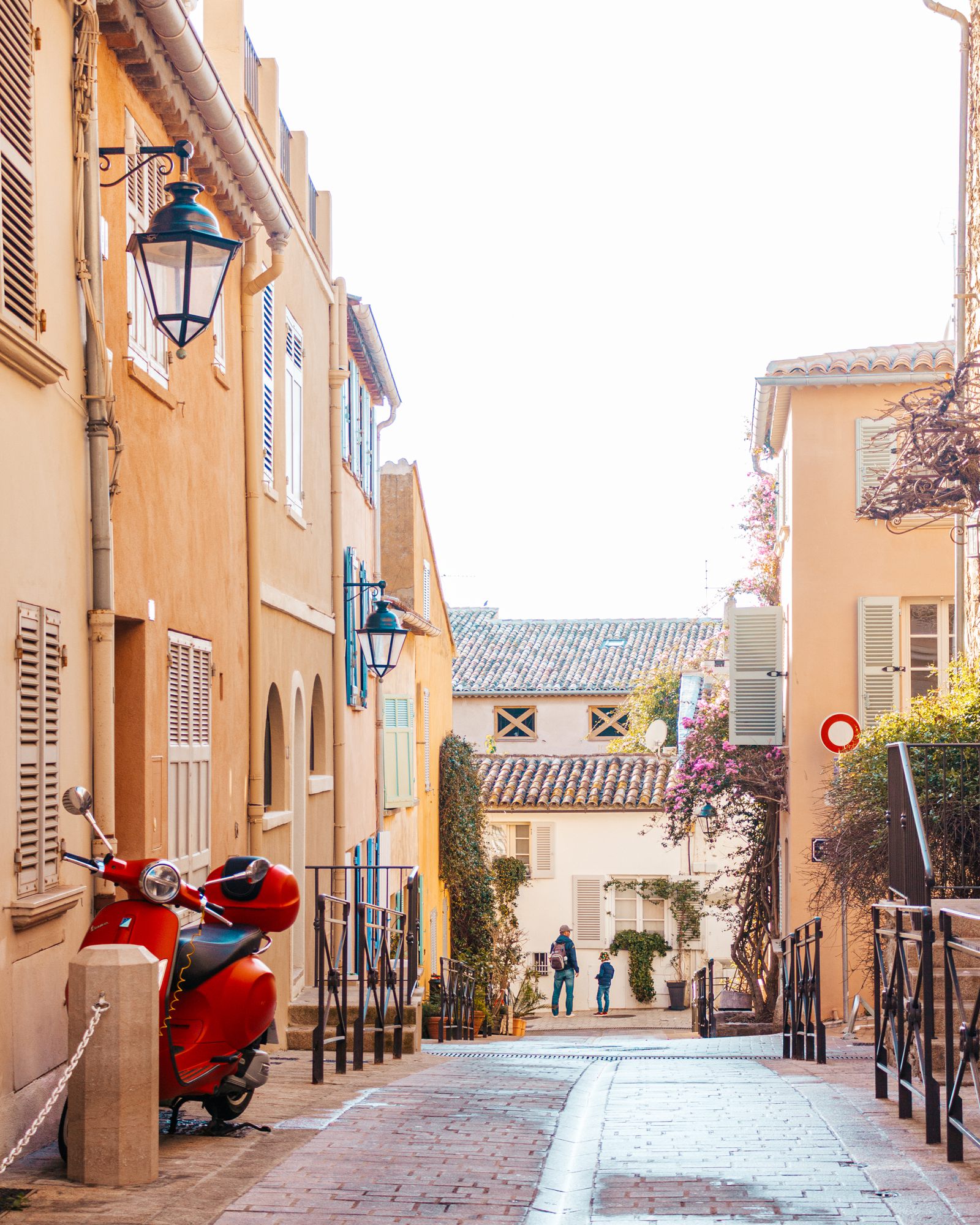 Narrow street with ochre houses and a red scooter
